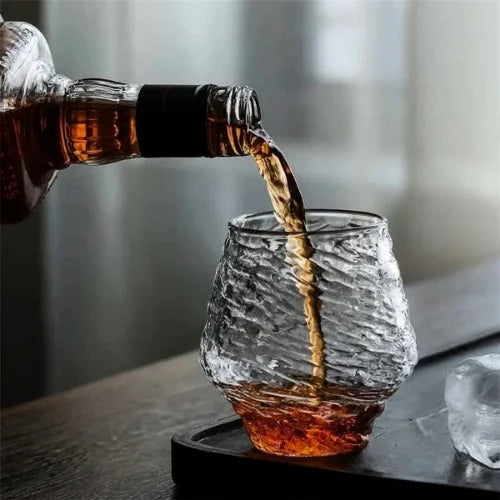 Le verre à whisky japonais tenu dans la main, mettant en avant sa texture irrégulière et son design inspiré de la nature.